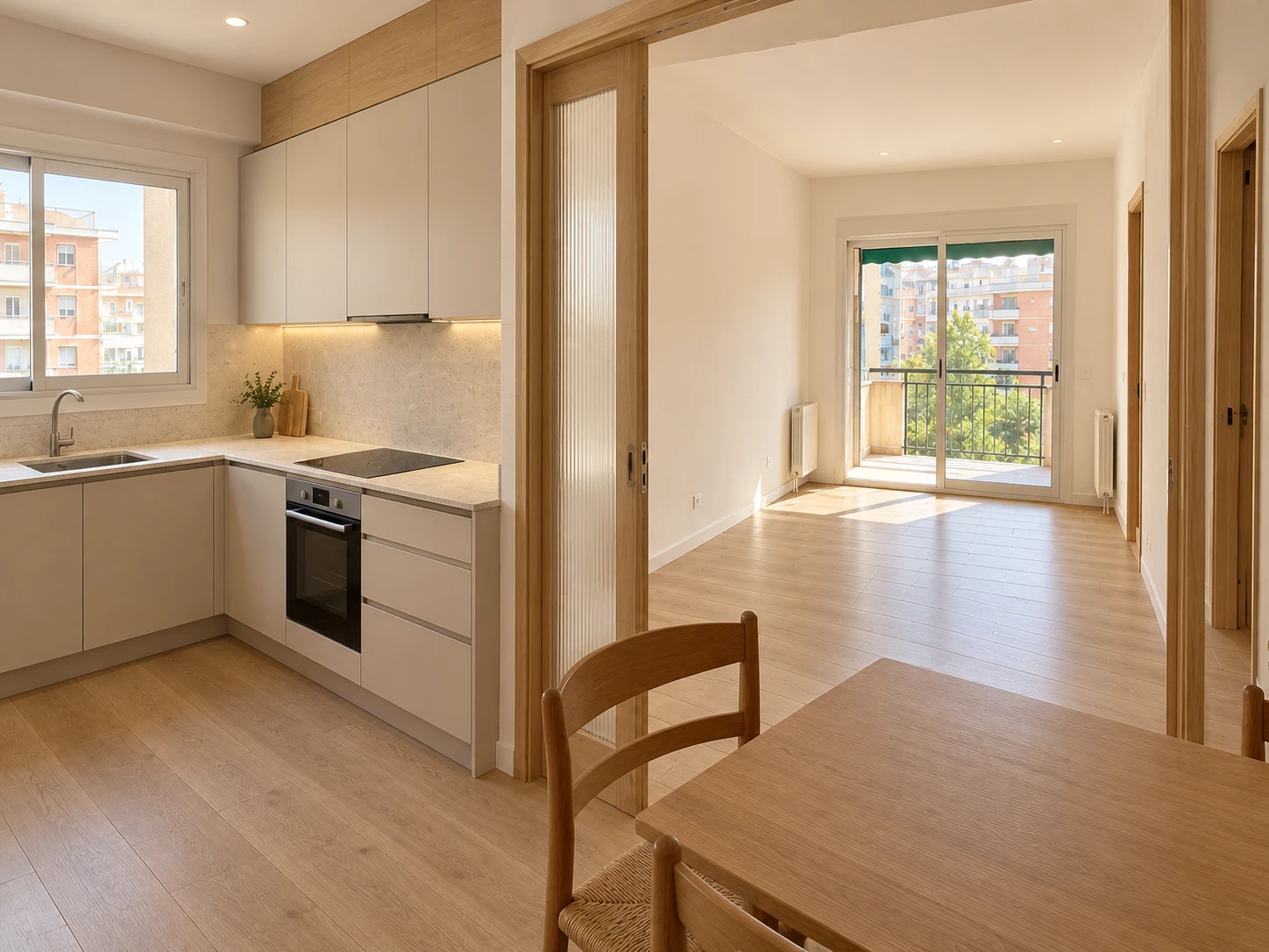 Posible resultado de la reforma: cocina con muebles lisos claros y encimera de piedra abierta a un salón luminoso con suelo de madera